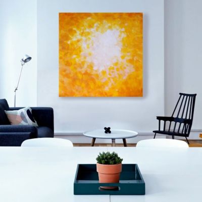 Painting in different shades of yellow and white on a white wall behind two armchairs and a table.