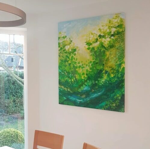 Painted picture in green, white and light blue tones hangs on the white wall behind the dining table and next to the window to the garden.